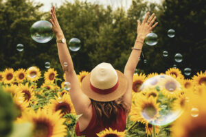 Mujer feliz entre girasoles y burbujas de jabón